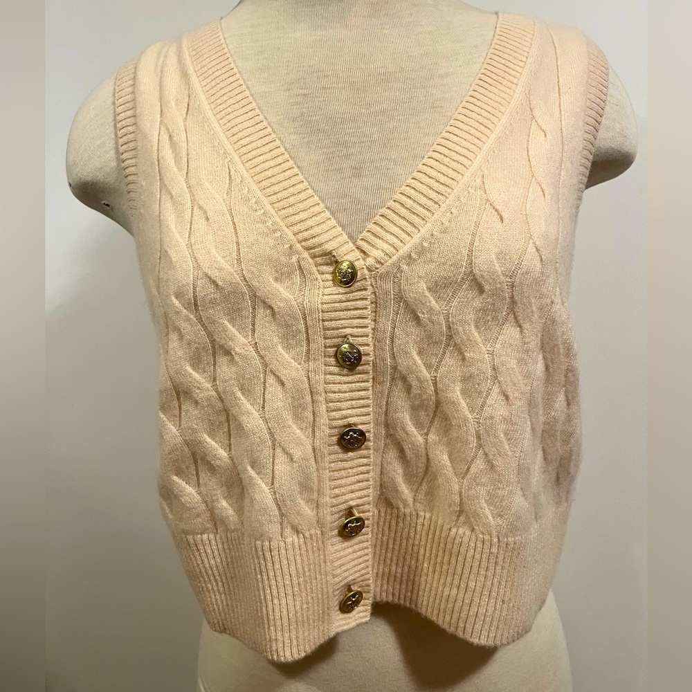 Cream-colored cable-knit sleeveless v-neck cardigan vest with brass(?) buttons